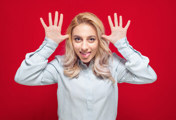 Funny young woman sticking tongue out, isolated on red background. Joke concept. Silly girl