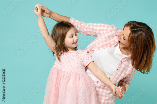 Happy woman in pink clothes have fun with cute child baby girl 5-6 years old. Mommy little kid daughter dancing celebrate isolated on pastel blue background studio. Mother's Day love family concept.