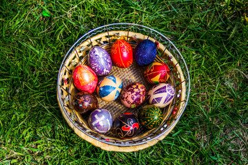 Defocus multicolored easter eggs. Decorated pysanka and krashanka. Wooden Basket With Easter Eggs In The Green Grass. Close-up. Top view. Handmade decor. Out of focus