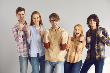 Group of happy excited cheerful young people in casual wear fist pumping and having fun celebrating achieving goal, sports team victory, business success, getting scholarship, winning education grant