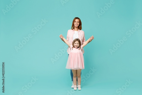 Full length happy woman in pink clothes have fun with cute child baby girl 5-6 years old. Mommy little kid daughter isolated on pastel blue azure background studio. Mother's Day love family concept.