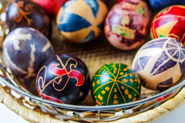 Defocus Easter eggs. Close-up round basket with colorful easter eggs on white background. Top view of part of green, blue, yellow, purple eggs. Perfect colorful handmade easter eggs. Out of focus