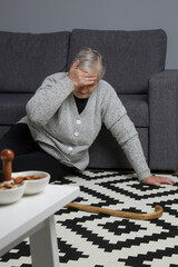 Senior woman lying on the floor in living room. Woman fell on the floor because of heart attack,...