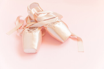 New pastel beige ballet shoes with satin ribbon isolated on pink background. Ballerina classical pointe shoes for dance training. Ballet school concept. Top view flat lay, copy space