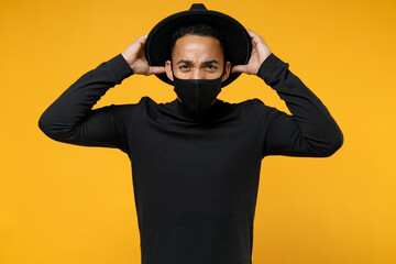 Young african confused worried man 20s in trendy stylish black hat shirt face mask to safe from...
