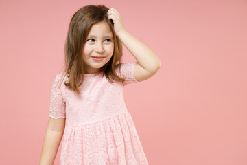 Little thoughtful cute kid girl 5-6 years old wears rosy dress have fun put hand on head isolated on pastel pink background child studio portrait. Mother's Day love family childhood lifestyle concept.