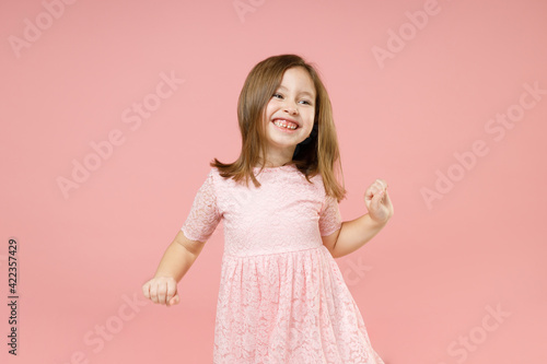 Little kid girl 5-6 years old wears rosy dress have fun dancing fooling around celebrate play fluttering hair isolated on pastel pink background child studio portrait Mother's Day love family concept