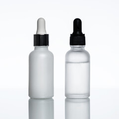 Bottles of serum on a light background. Moisturizer, vitamin C, hyaluronic acid.