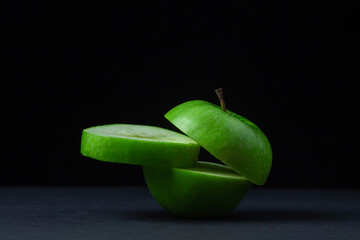 Green apple on a dark background. A cut green apple on a black background. Healthy food