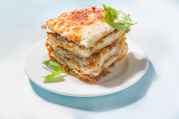 Mediterranean food, Italian traditional lasagna pasta, with bolognese, bechamel and cheese. On trendy breght light blue background with hard light and dark shadows copy space