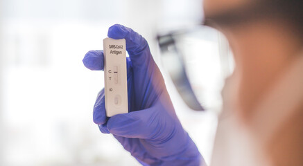 Young biologist or pharmacist is holding a covid-19 or corona antigen test