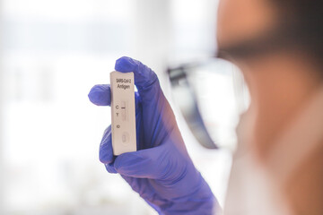 Young biologist or pharmacist is holding a covid-19 or corona antigen test