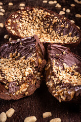 Stuffed chocolate easter egg with peanut and caramel on a wooden table with lots of peanuts around. Cracked. Close up.