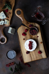 Different kinds of cheese on the wooden board with berries