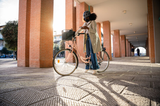 Portrait of a young commuter woman in the city in the sustainable home-to-work path wearing face mask against Coronavirus Covid-19 pandemic uses smartphone to check emails - Safety commuting concept