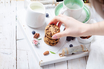 Female hands preparing breakfast with cookies on a white wooden tray for mom's day