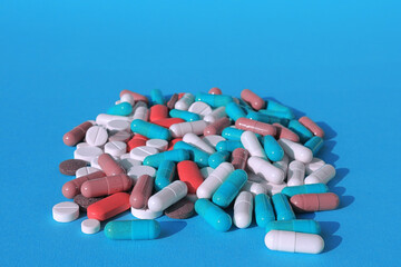 tablets, pills and capsules - medicines are poured on a blue background.