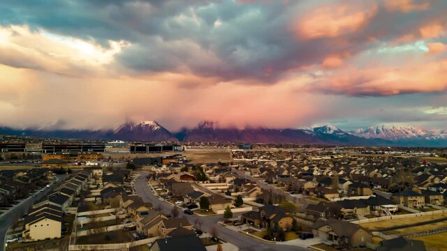 Aerial hyperlapse of a localized snow flurry in the mountains with the colors of the setting sun on the clouds
