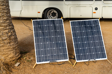 mobile solar panels next to a palm tree with a large RV motor home behind
