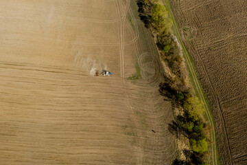 Aerial view large tractor cultivating a dry field. Top down aerial view tractor cultivating ground...