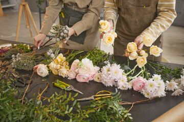 Background image of beautiful flowers on table in flower shop with two unrecognizable florists...