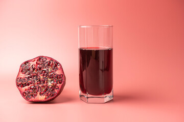 a glass of pomegranate juice and pomegranates on a red background