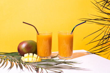 Glass of fresh mango juice cocktail and palm branches