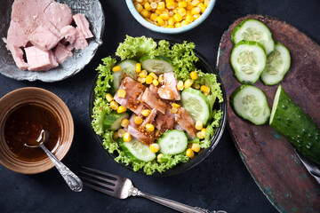 fresh tuna salad with corn and lettuce leaves, sauce and fresh cucumbers, flatlay