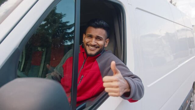Young indian man showing thumb up through the window of the van. High quality 4k footage