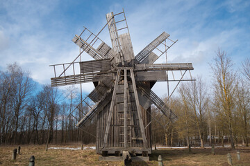 old wooden mill against the sky and spring forest