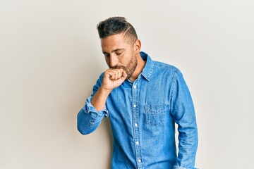 Handsome man with beard wearing casual denim jacket feeling unwell and coughing as symptom for cold...