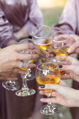 Champagne glasses in women's hands. Wedding morning bridal party. People clinking wine glasses.