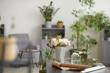 Background image of beautiful flowers in buckets and jars on table in florist workshop decorated by green plants, copy space