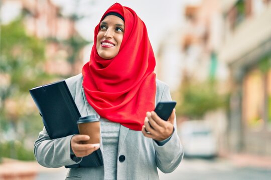 Young arab businesswoman using smartphone and drinking coffee at the city.