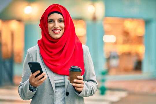 Young arab businesswoman using smartphone and drinking coffee at the city.
