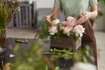 Cropped portrait of unrecognizable young woman arranging flower composition with pink peonies while...