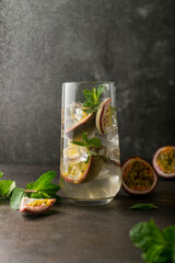 refreshing drink with passion fruit. cocktail with tropical fruit on a dark background. with green mint leaves. vertical position