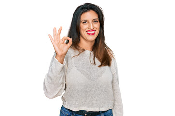 Beautiful hispanic woman wearing casual sweater smiling positive doing ok sign with hand and fingers. successful expression.