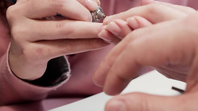 Close up view of manicurist removing dry skin from nails on man's hands. Russian manicure.