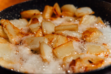 Chunks of potatoes are fried in boiling oil. Close-up photo of cooking junk food.