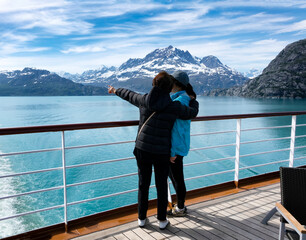 Mother holding her daughter while pointing to mountains and glaciers in Alaska while on ship - 422370217