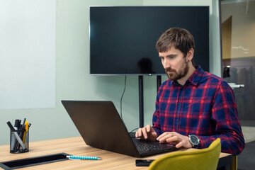 Young businessman working at the desk in the office with a laptop. Work, businessman, business