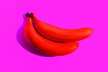 Two ripe red bananas cast a shadow isolated on a bright purple background