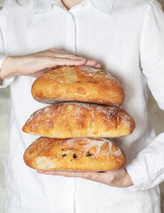 Female baker holds home made artisan organic bread fresh from the oven. Homemade sourdough bread. Homemade food.
