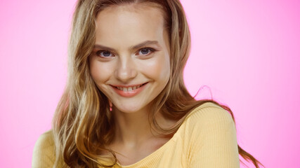 Fototapeta premium cheerful young woman with wavy hair isolated on pink