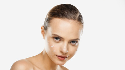 Fototapeta premium sensual young woman with bare shoulders and cream on face looking at camera isolated on white
