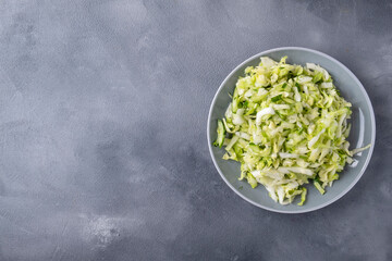 Fresh cabbage salad with cucumber and dill on a plate. Top view, text space