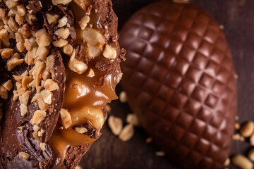 Close up of a stuffed chocolate easter egg with peanut and caramel on a wooden table with lots of...