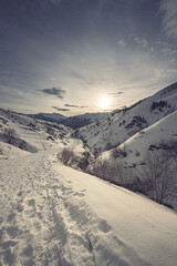 Paysage de montagne dans la vallée Perdue en contre jour face au soleil levant sur un chemin...