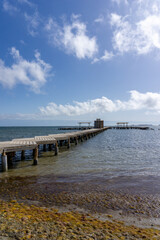 Fototapeta na wymiar wooden boardwalk leading out into the ocean to a public bath installation